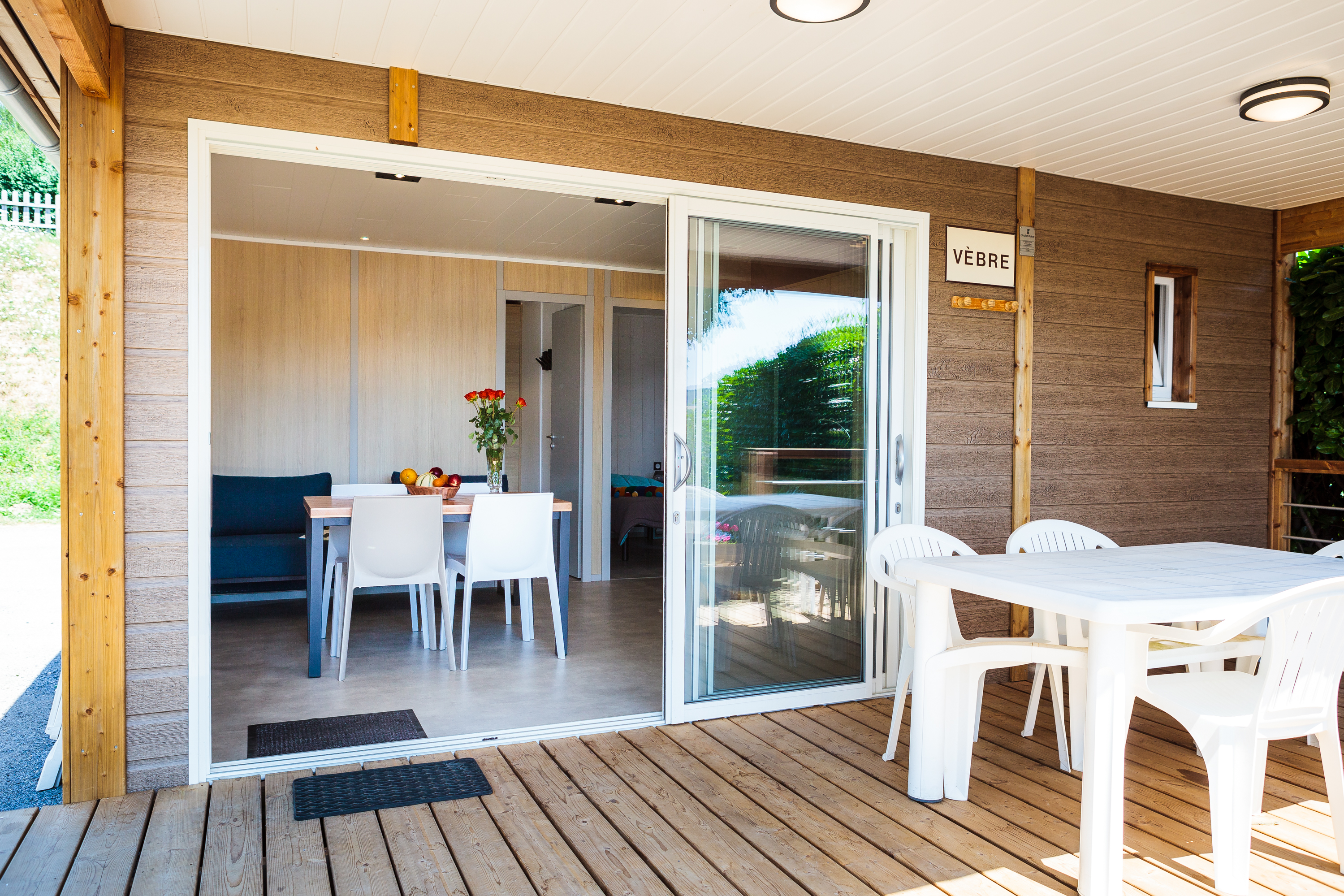 la terrasse et la pièce à vivre du chalet lac par une baie vitrée rétractable